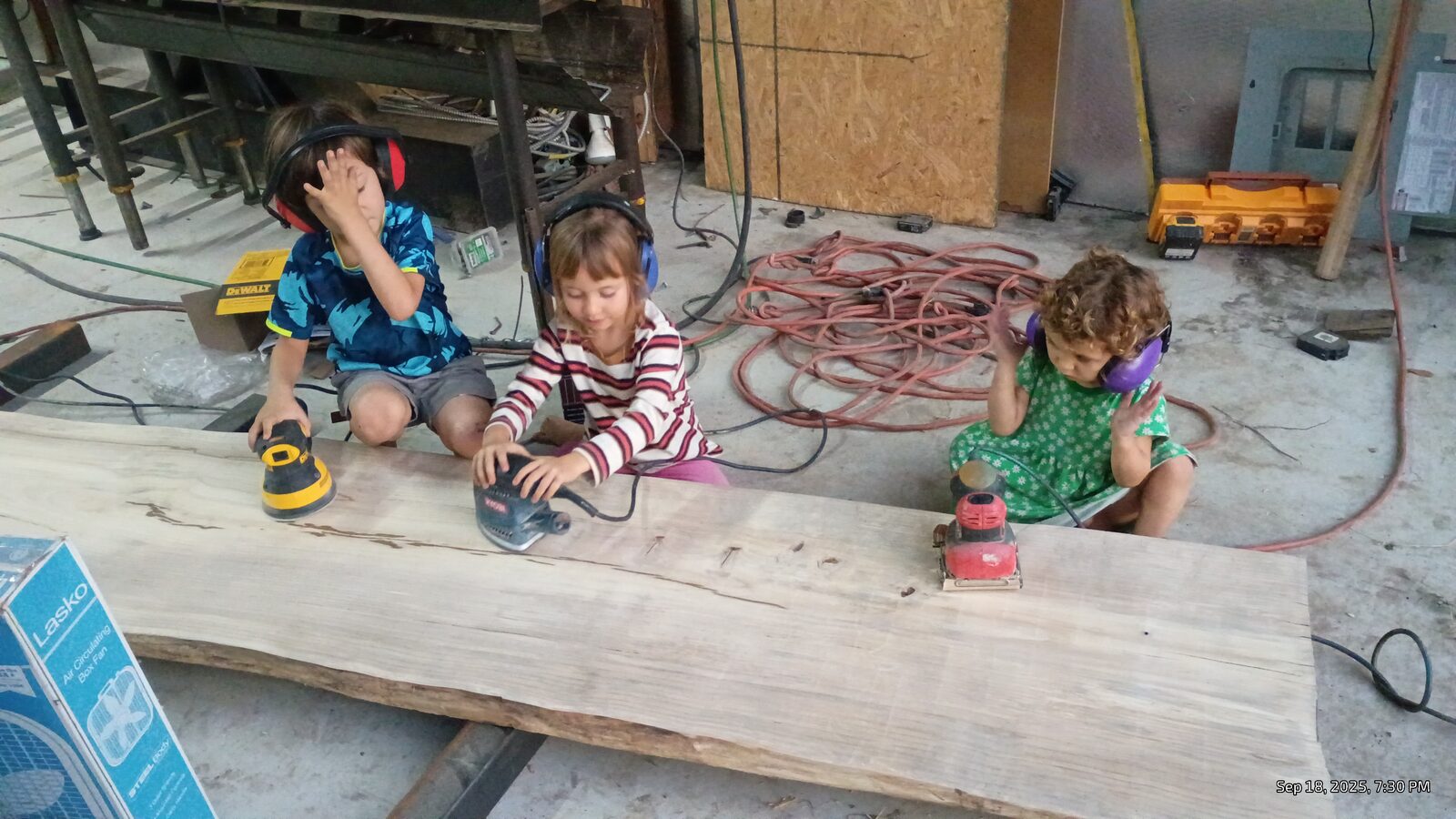 The sanding crew — all three kids with sanders and ear protection