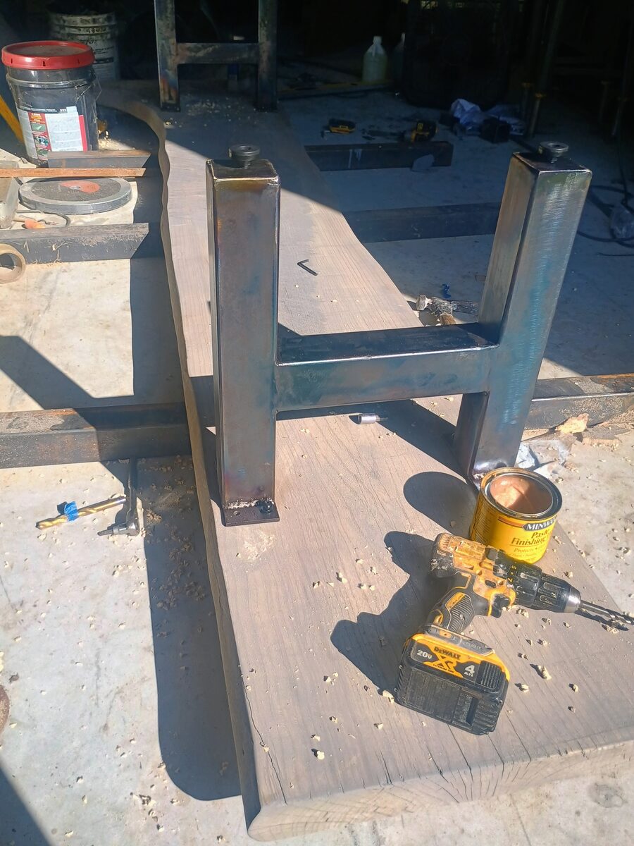 Steel legs mounted on the hackberry slab — drill and finish can visible
