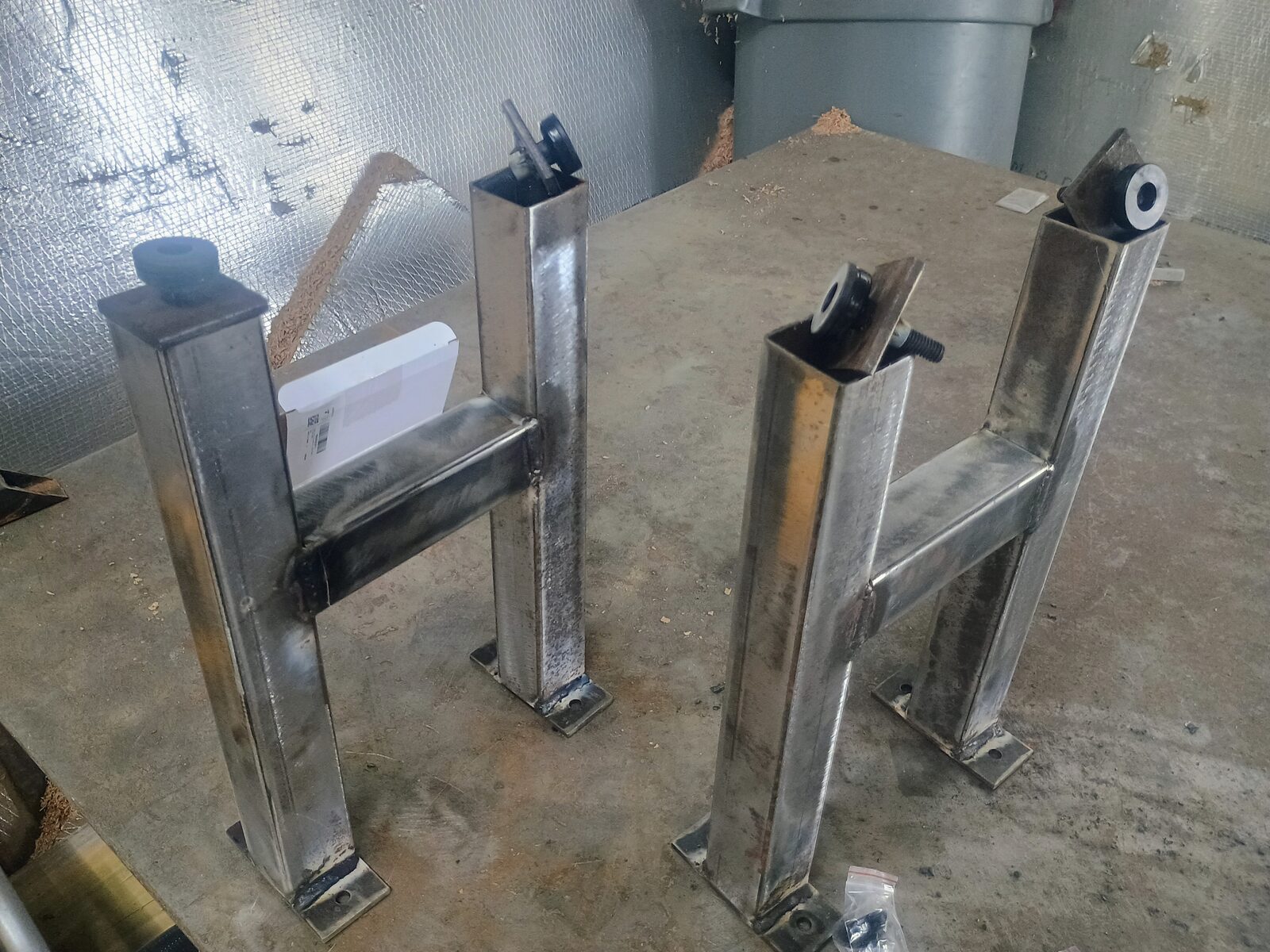 Two pairs of freshly welded H-frame steel legs with leveling feet