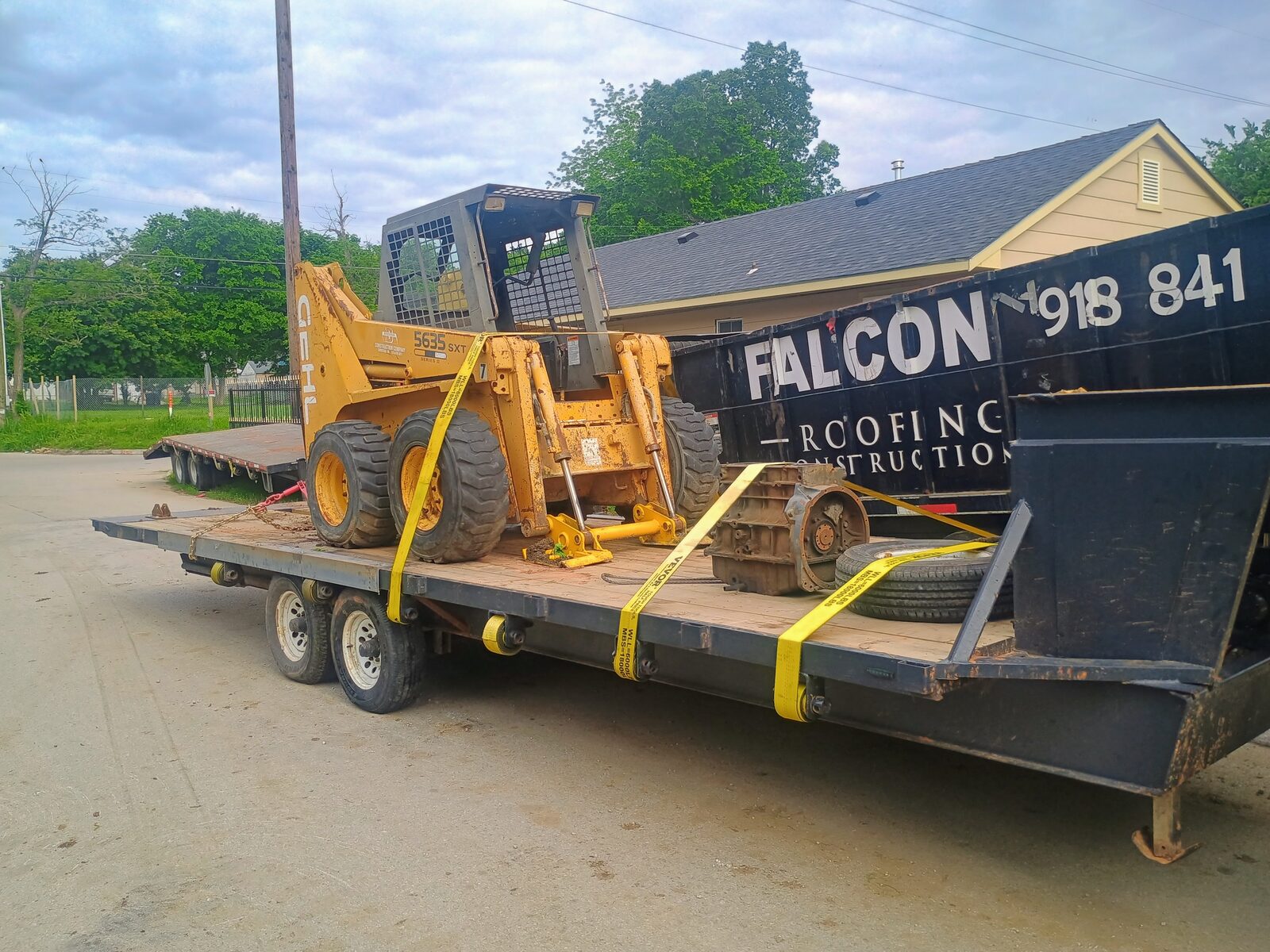 Skid steer strapped on the flatbed with extra parts