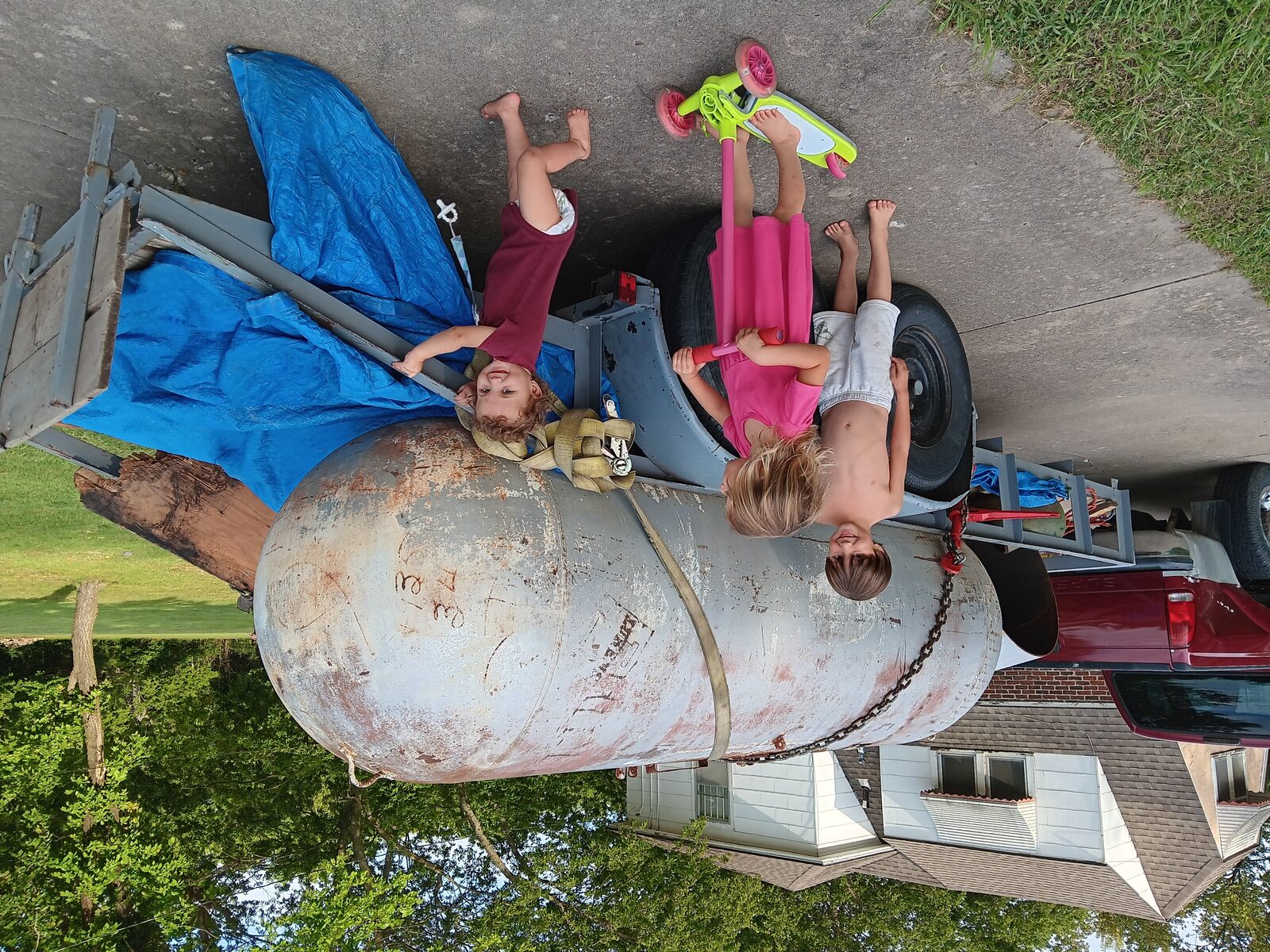 The propane tank arrives — kids for scale